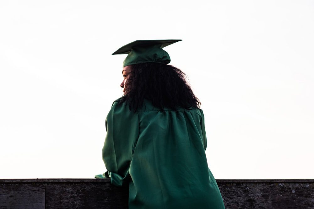 a woman wearing a green graduation toga