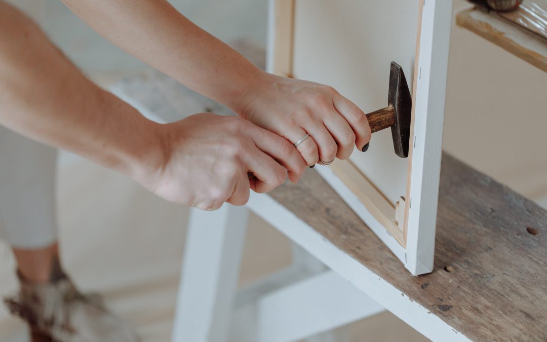 Close-up of hands using a hammer to assemble or hang a canvas print